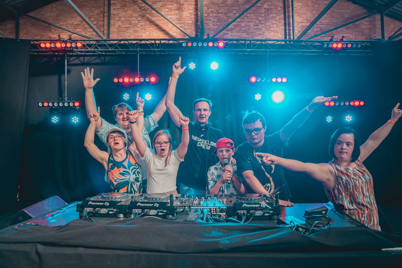 Een groep bezoekers steekt de handen in de lucht aan de dj-booth op een vorige editie van Grenzeloos Festival.