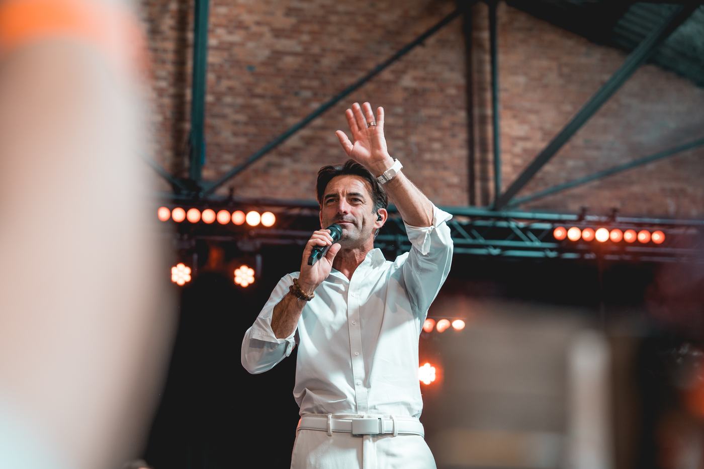 Een presentator zwaait naar het publiek met de microfoon in de hand.