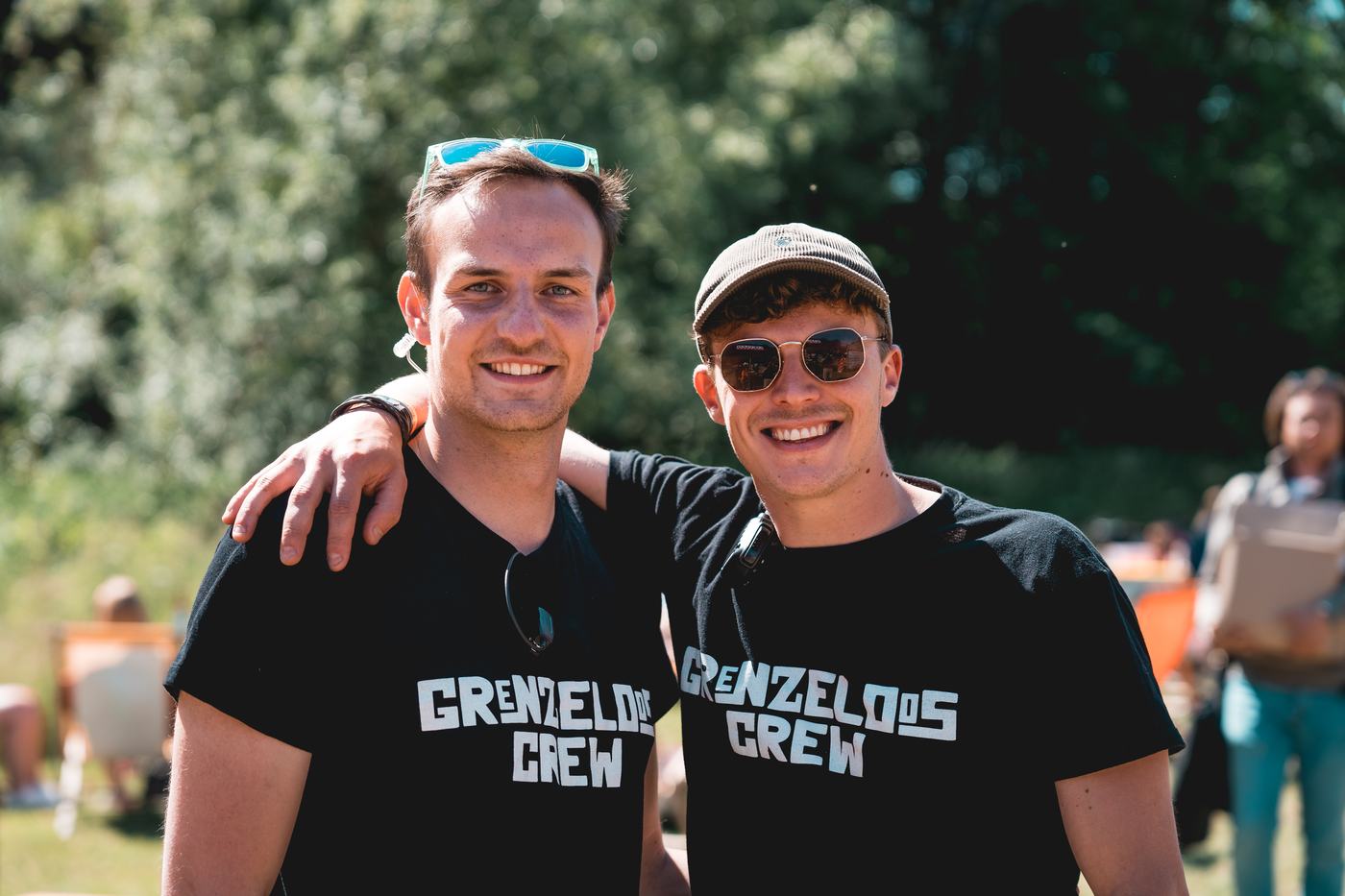 Twee vrijwilligers van de Grenzeloos Crew met de arm om elkaars schouder.