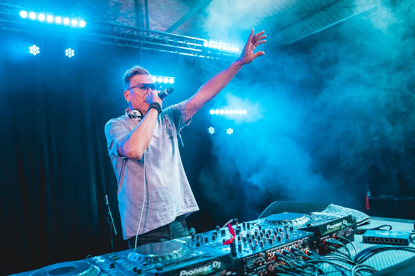Een dj zingt mee met de muziek onder blauwe lichten.