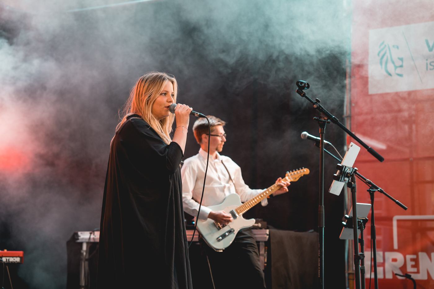 Een zangeres en gitarist brengen een liveset op het podium.